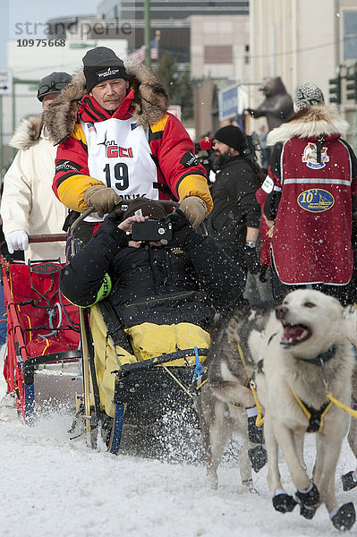 Mitch Seavey und sein Team verlassen die feierliche Startlinie mit einem Iditarider während des Iditarod 2016