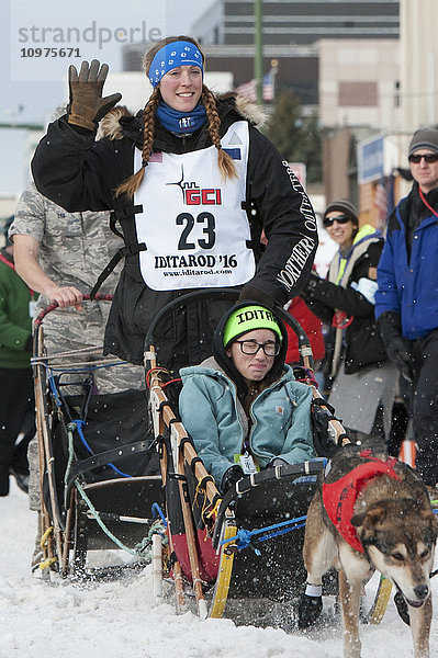 Anna Berington und ihr Team verlassen die feierliche Startlinie mit einem Iditarider während des Iditarod 2016
