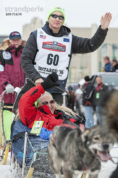 Ray Redington Jr. und sein Team verlassen die feierliche Startlinie mit einem Iditarider während des Iditarod 2016