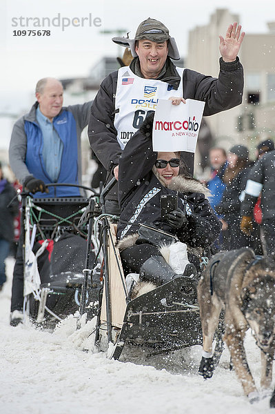 John Baker und sein Team verlassen die feierliche Startlinie mit einem Iditarider während des Iditarod 2016