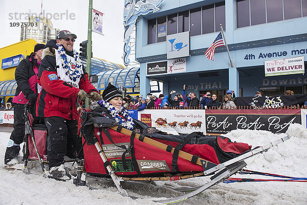 Paul Gebhardt und sein Team verlassen die feierliche Startlinie mit einem Iditarider während des Iditarod 2016