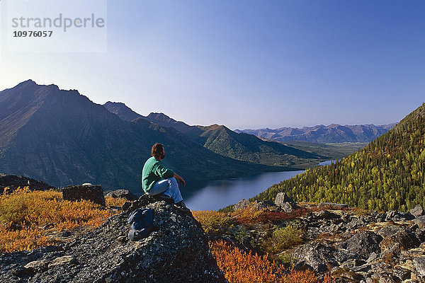 Wanderer sitzt auf einem Felsen über dem Selby Lake Brooks Range Gates Of The Arctic National Park Herbst Alaska/N