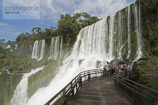 Metallsteg  der zu den Iguazu-Fällen führt  mit einem Regenbogen über dem Wasser; Missiones  Argentinien'.