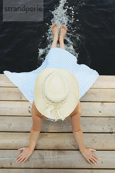 Mädchen mit Strohhut  das am Ende eines Stegs sitzt und die Füße ins Wasser hält; Ontario  Kanada'.