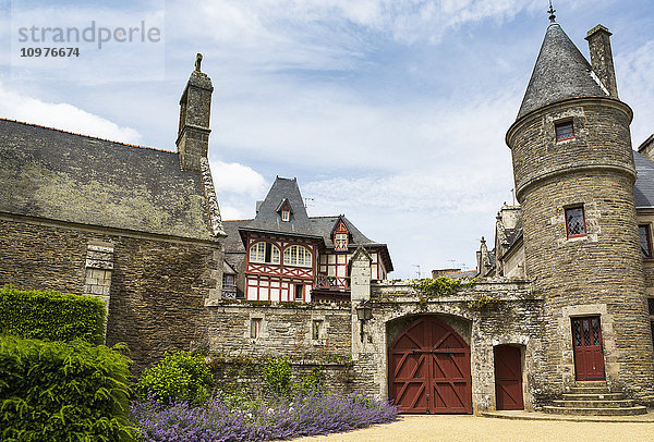Alter steinerner Schlossturm und Kirche mit großen Holztoren in Steinmauer mit blauem Himmel und Wolken; Josseline  Bretagne  Frankreich'.