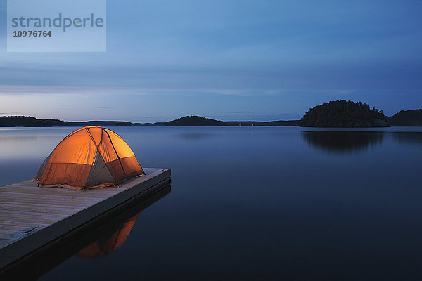 Beleuchtetes Zelt auf dem Steg bei Sonnenuntergang am Mara Lake; Ontario  Kanada