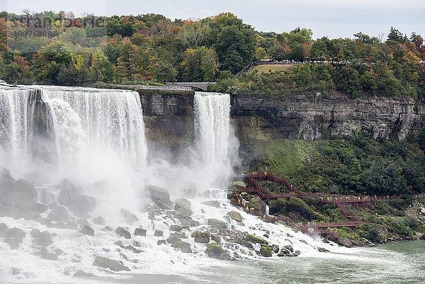 American Falls und Touristen in gelben Regenmänteln  die den Steg erklimmen; Niagara Falls  New York  USA'.