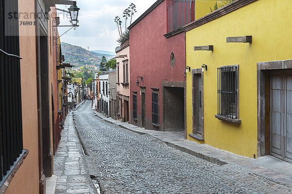 Bunte Gebäude entlang einer Kopfsteinpflasterstraße; San Miguel de Allende  Guanajuato  Mexiko'.
