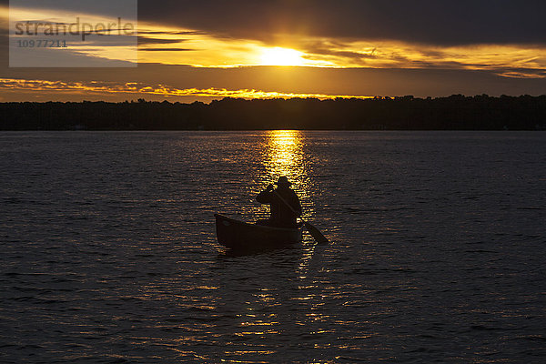 Mann paddelt Kanu bei Sonnenaufgang auf dem Balsam Lake; Ontario  Kanada'.