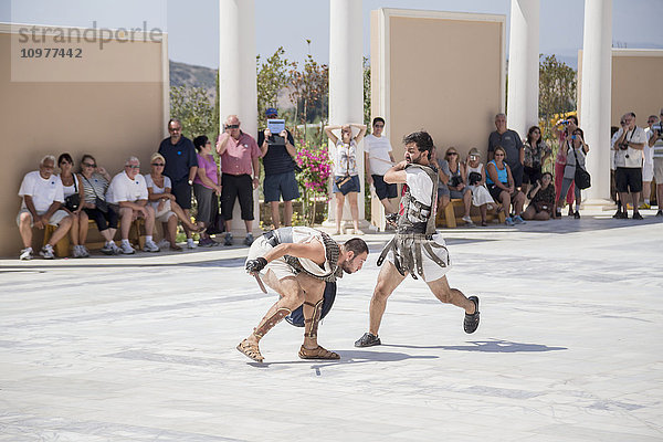 Zwei als Gladiatoren verkleidete Schauspieler kämpfen in einem Duell vor einer Touristenmenge in einer Attraktion zur griechischen Geschichte in der Türkei; Kusadasi  Izmir  Türkei'.