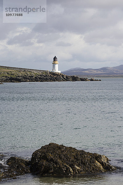 Leuchtturm an der Wasserkante bei bewölktem Himmel; Port Charlotte  Isle of Islay  Schottland .
