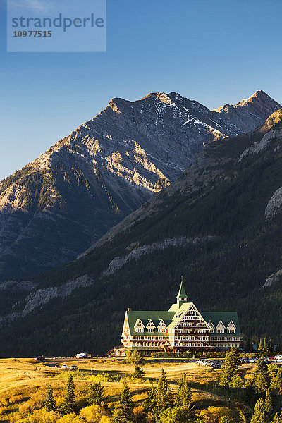 Prince of Wales Hotel auf einer Bergkuppe bei Sonnenaufgang mit Bergen und blauem Himmel im Hintergrund; Waterton  Alberta  Kanada'.