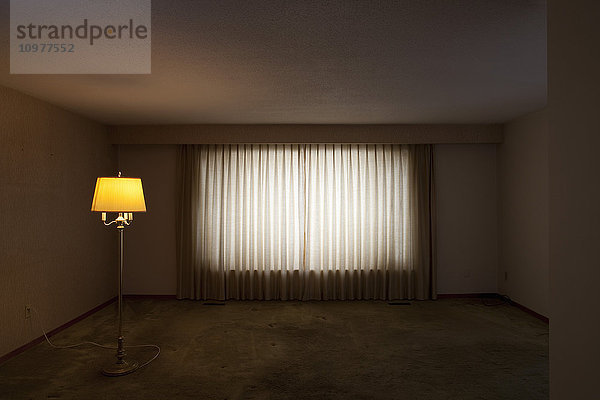 Leeres Wohnzimmer mit einer beleuchteten Stehlampe
