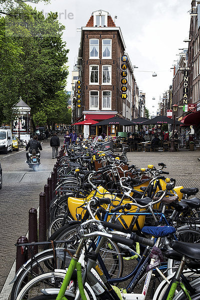 Zahlreiche Fahrräder in einer Reihe entlang einer Straße; Amsterdam  Niederlande'.
