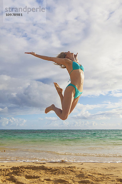 Frau im Bikini  die am Strand in die Luft springt; Kailua  Insel Hawaii  Hawaii  Vereinigte Staaten von Amerika'.