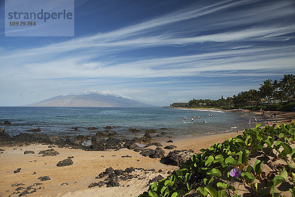 Zirruswolken  Keawakapu Beach mit einheimischen Pohuehue-Blüten (Ipomoea pes-caprae) und Schwimmern  Kihei und Wailea Beach mit West Maui Mountains; Kihei  Maui  Hawaii  Vereinigte Staaten von Amerika'.