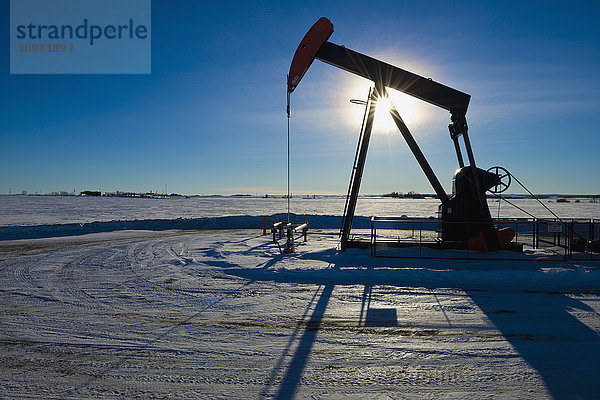 Silhouette eines Ölpumpenhebers mit Sonnenstern; Morinville  Alberta  Kanada'.