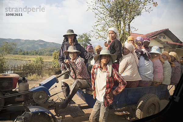 Weibliche Straßenbauarbeiter warten darauf  mit Karren und Traktoren zu ihrer Arbeitsstelle gebracht zu werden; Myanmar'.