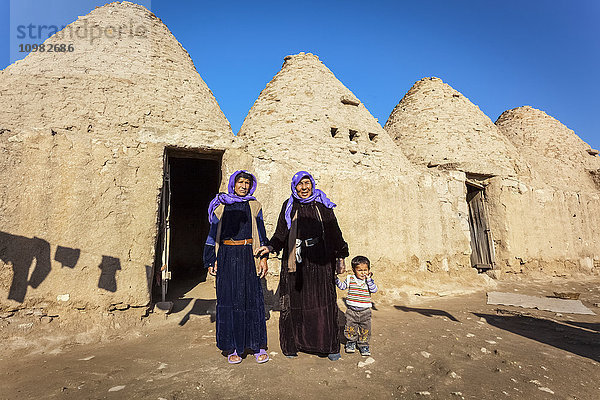 Zwei Frauen und ein Kind stehen vor der Tür einer primitiven Behausung; Harran  Türkei .