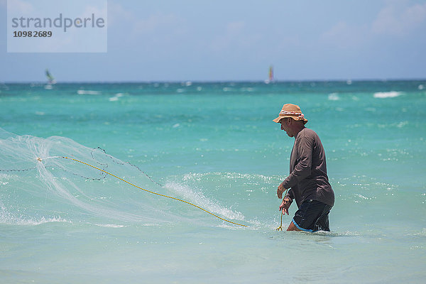 Ein kubanischer Fischer wirft an einem sonnigen Tag ein Netz im karibischen Meer aus  um Fische im blauen Wasser zu fangen; Varadero  Kuba'.