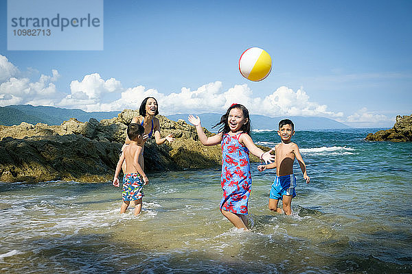 Mother and three children playing with beach ball