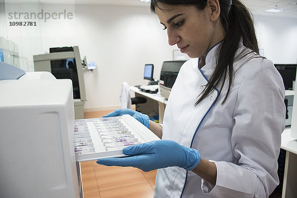 Labortechniker im analytischen Labor beim Einlegen von Objektplatten in den Zytologieleser