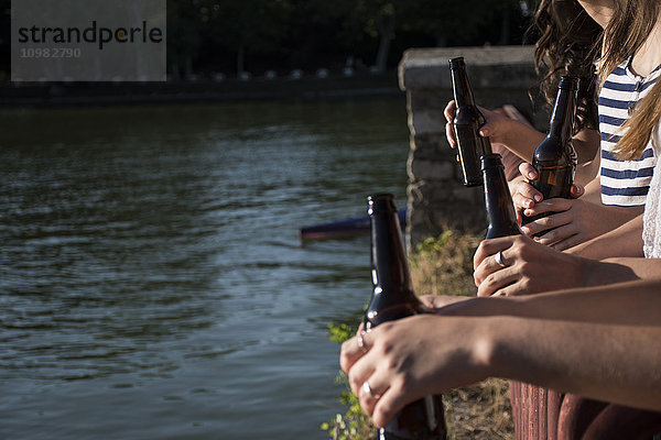 Freunde  die gemeinsam bei Sonnenlicht Bier trinken  Teilansicht