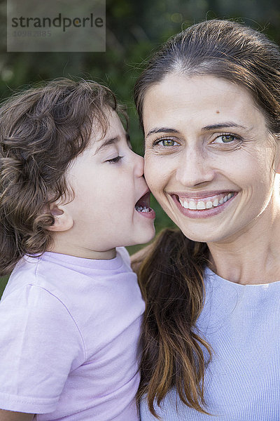 Porträt einer glücklichen Mutter mit einer kleinen Tochter  die sie küsst.