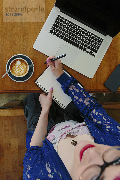 Junge Frau mit Laptop und Notebook im Café  Draufsicht