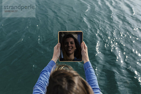 Junge Frau  die einen Selfie mit digitalem Tablett am Wasser nimmt