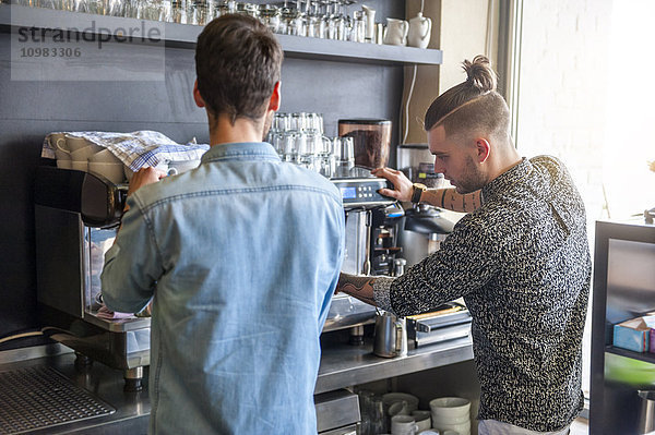Zwei Männer bereiten Kaffee in einem Café zu.