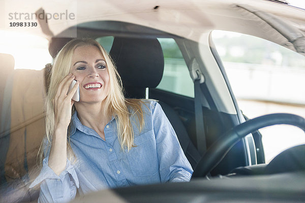 Lächelnde Frau im Auto am Handy