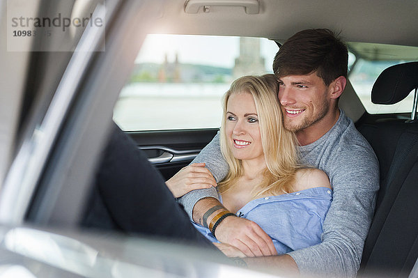 Lächelndes verliebtes Paar auf dem Rücksitz eines Autos