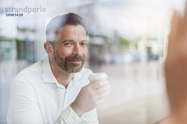 Porträt eines lächelnden Geschäftsmannes in einem Café mit Blick durchs Fenster