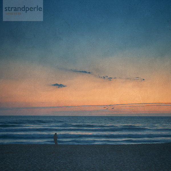 Silhouette des Mannes am Strand bei Sonnenuntergang