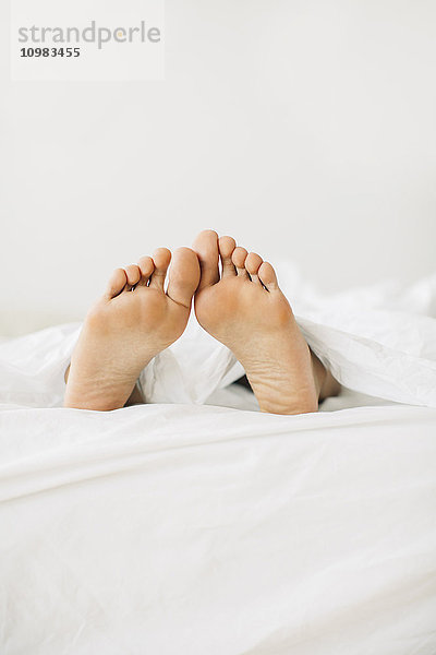 Füße der Frau im Bett liegend