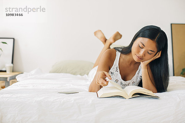 Junge Frau im Bett liegend Lesebuch