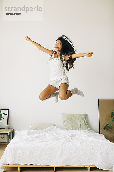 Überschwängliche junge Frau beim Springen auf dem Bett