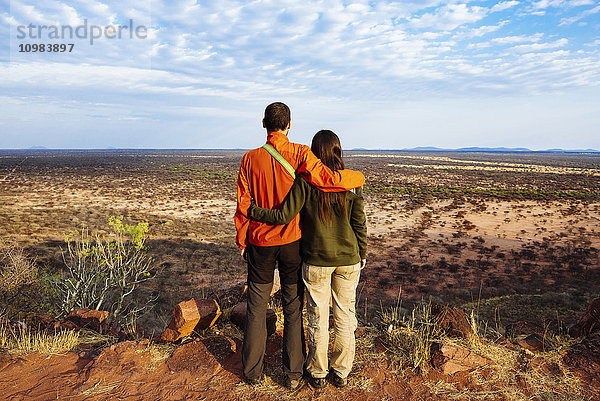 Namibia  umarmendes Paar  das die weiten Ebenen der afrikanischen Savanne von einem natürlichen Standpunkt aus betrachtet.