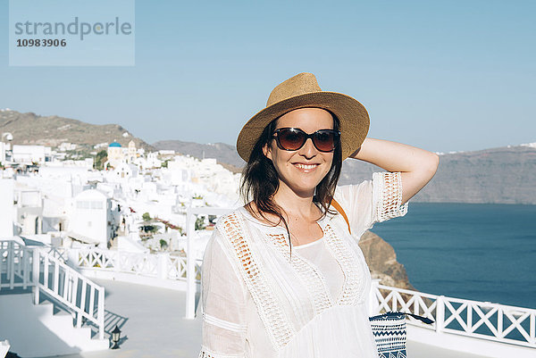 Griechenland  Santorini  Oia  Porträt der lächelnden Frau mit Sonnenbrille und Strohhut