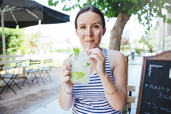 Glückliche Frau trinkt im Sommer hausgemachte Limonade