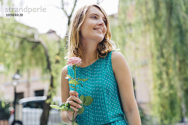 Lächelnde junge Frau mit Rosenblüte