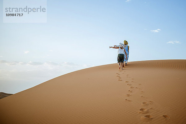 Berbermann und Berberin  die in der Wüste spazieren gehen  nach links zeigend