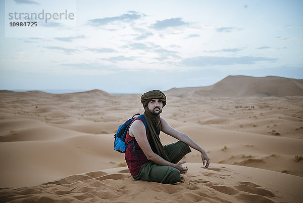 Tourist mit Turban in der Wüste sitzend