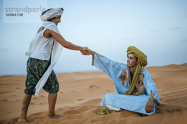 Frau hilft ihrem Berberführer vom Boden aufzustehen