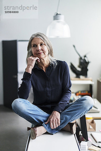 Seniorin auf einem Schrank im Büro sitzend