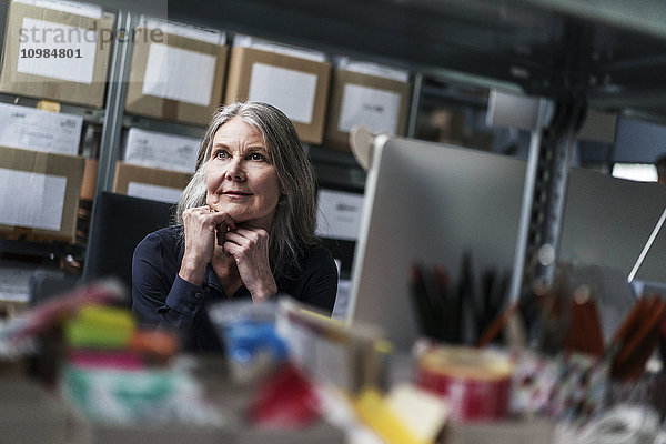 Seniorin am Schreibtisch einer Fabrik