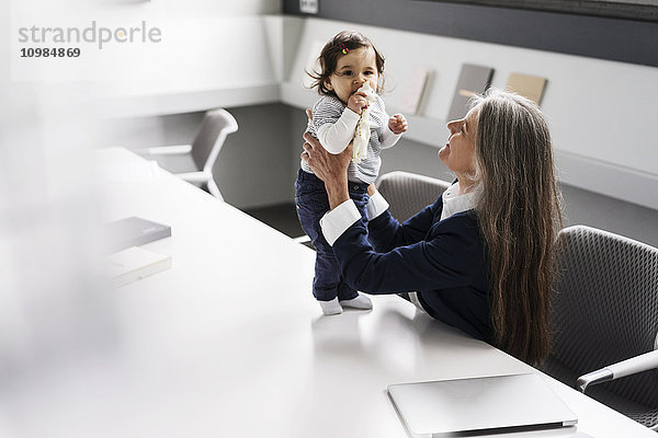 Senior Geschäftsfrau im Konferenzraum mit Baby Girl