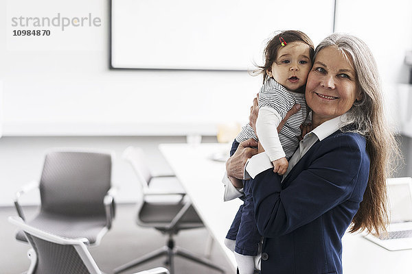 Senior Geschäftsfrau im Konferenzraum mit Baby Girl