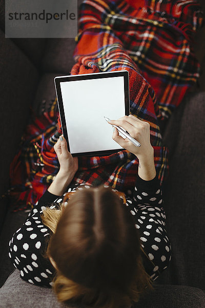 Junge Frau entspannt auf der Couch  Zeichnung auf Tablett mit Stift  Draufsicht